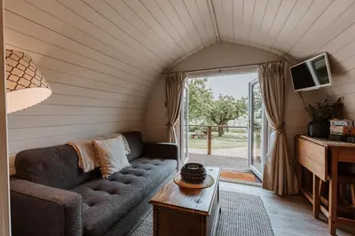 a living room with a couch and a tv at Secluded Cosy Luxury Pod with wood fired hot tub in Shrewsbury