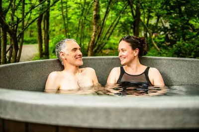 a man and a woman sitting in a hot tub at Cosy Shepherd's Hut with Hot Tub in Church Stretton