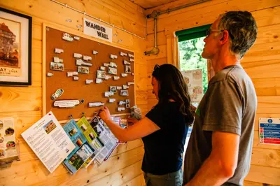 a man and a woman looking at a poster on a wall at Cosy Shepherd's Hut with Hot Tub in Church Stretton