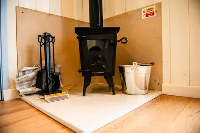 a stove sitting in the corner of a room at Cosy Shepherd's Hut with Hot Tub in Church Stretton