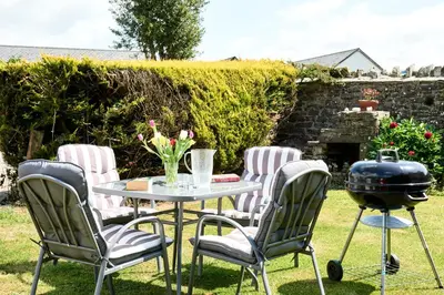 a table and chairs and a grill in a yard at Trefaen Cottage in Brecon