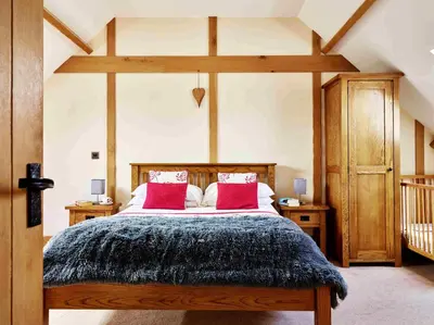 a bedroom with a large bed with red pillows at Trefaen Cottage in Brecon
