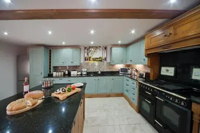 a kitchen with blue cabinets and a black counter top at Oak Barn in Brecon