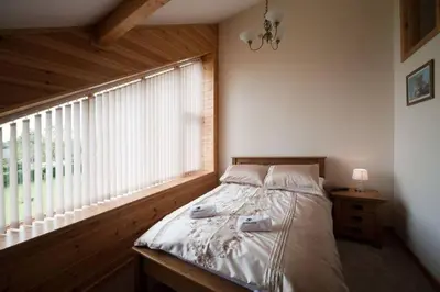 a bed in a room with a large window at Poplar Tree Eco Lodge in Brecon
