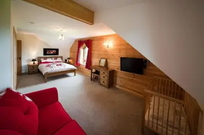 a living room with a red couch and a bedroom at Poplar Tree Eco Lodge in Brecon
