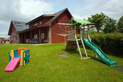a playground with a slide in the yard of a house at Poplar Tree Eco Lodge in Brecon