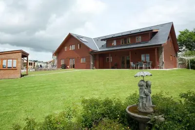 a house with an umbrella in front of a yard at Poplar Tree Eco Lodge in Brecon