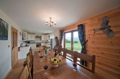 a kitchen and dining room with a table and a bird on the wall at Beech Tree Eco Lodge in Brecon