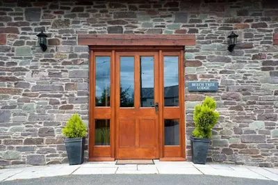 a wooden door on a stone building with two potted plants at Beech Tree Eco Lodge in Brecon