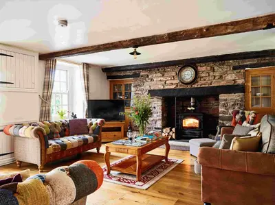 a living room with couches and a stone fireplace at Onnen Fawr Farmhouse in Brecon