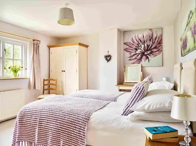 a bedroom with a large white bed with a flower painting on the wall at Onnen Fawr Farmhouse in Brecon