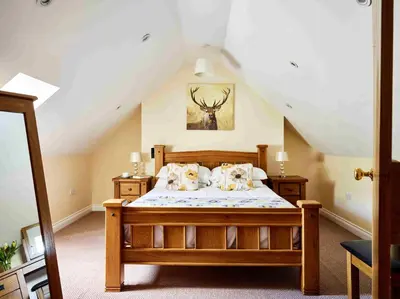 a bedroom with a wooden bed in a attic at The Ash Cottage in Brecon