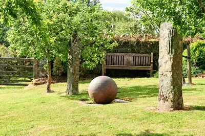 a large ball sitting in the grass next to a bench at The Ash Cottage in Brecon