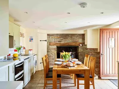 a kitchen with a wooden table with chairs and a fireplace at The Ash Cottage in Brecon