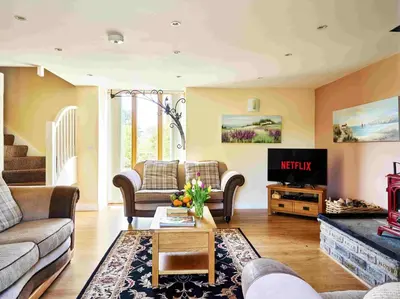 a living room with couches and a tv at The Ash Cottage in Brecon