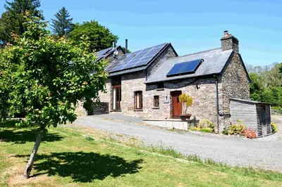 an old stone house with solar panels on the roof at The Ash Cottage in Brecon