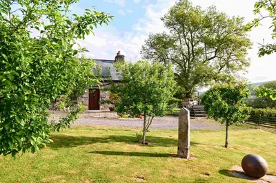 an old house with two trees in the yard at The Ash Cottage in Brecon