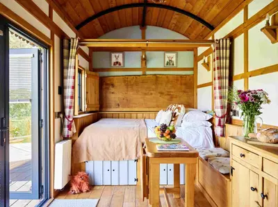 a bedroom in a house with a bed and a table at The Flying Scotsman Shepherd's Hut with Hot Tub in Brecon