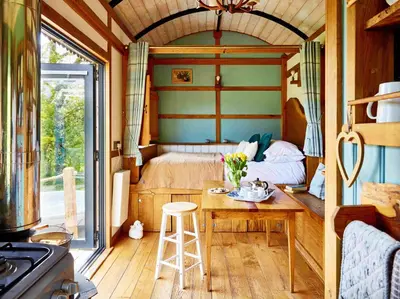 a small bedroom with a bed and a table with a stool at The Orient Express Shepherd's Hut with Hot Tub in Brecon