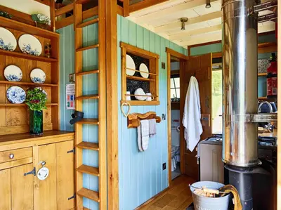 a kitchen with wooden cabinets and a blue door at The Orient Express Shepherd's Hut with Hot Tub in Brecon