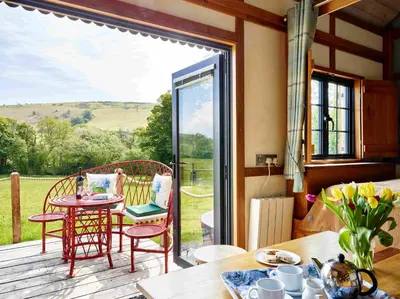 a room with a deck with a table and chairs at The Orient Express Shepherd's Hut with Hot Tub in Brecon