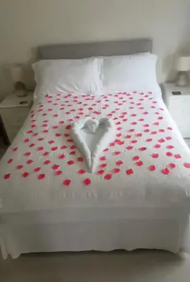 a white heart on a bed with red pedals at Bryntirion Farmhouse Apartment with Hot Tub in Llanfair Caereinion