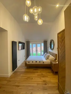 a bedroom with a bed and a window and chandeliers at Dave & Kelz Deluxe king size studio room in Builth Wells