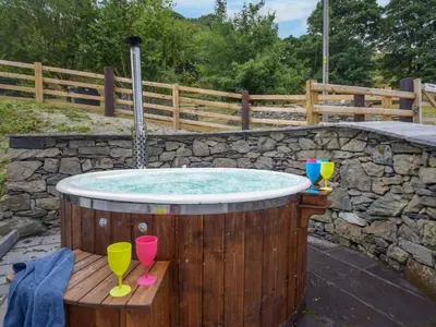 a hot tub with two wine glasses on a wooden deck at 3 Bed in Corwen oc-86266 in Corwen