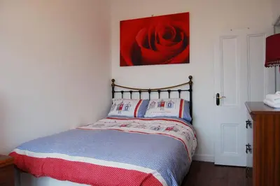 a bedroom with a bed with a red rose on the wall at Beach Vista Apartment One in Barmouth in Barmouth