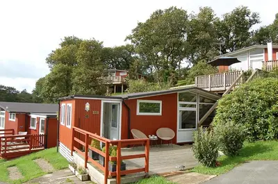 a red tiny house with a porch and a deck at Bryniau Gwyrdd Chalet 11 Happy Valley in Tywyn