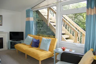 a living room with a yellow couch and a large window at Bryniau Gwyrdd Chalet 11 Happy Valley in Tywyn