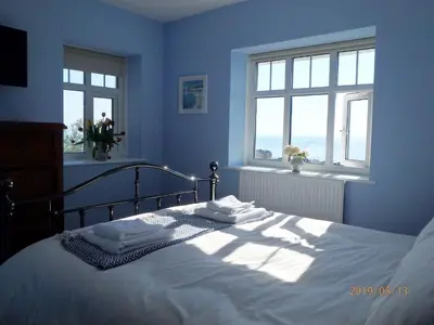 a blue bedroom with a bed with two windows at Bryn Mair in Barmouth in Barmouth