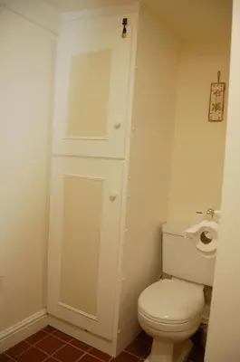 a bathroom with a white toilet and a toilet paper dispenser at Bronhaul Cottage in Pennal in Pennal