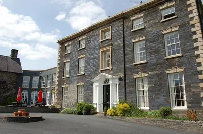 a large brick building with a white door at Bronhaul Cottage in Pennal in Pennal