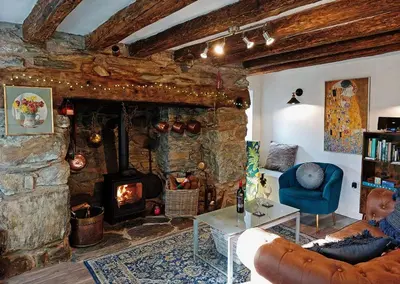 a living room with a stone fireplace and a blue chair at Cae Tudur Remote Rural Cottage near Barmouth in Barmouth
