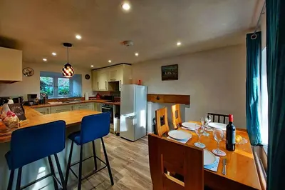 a kitchen with a dining table and a refrigerator at Cae Tudur Remote Rural Cottage near Barmouth in Barmouth