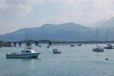 a group of boats in the water near a bridge at Hafan Y Traeth Beach Front Apartment in Barmouth in Barmouth