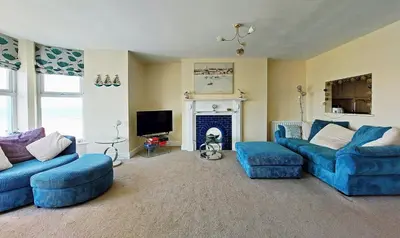 a living room with two blue couches and a fireplace at Hafan Y Traeth Beach Front Apartment in Barmouth in Barmouth