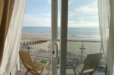a view of a beach from a balcony with chairs at Chwerthin Y Mor Beach House in Tywyn