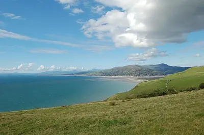 a view of a beach and the ocean on a hill at Chwerthin Y Mor Beach House in Tywyn