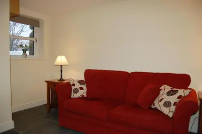 a red couch in a living room with a lamp at Anneddle Cottage in Talybont, near Barmouth in Talybont