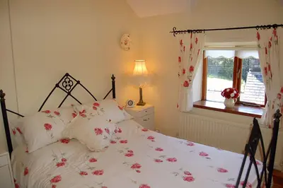 a bedroom with a bed with pink flowers on it at Tre-Allt Gorgeous Cottage in Dolgellau