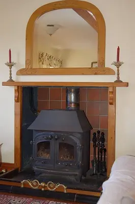 a wood stove in a room with a mirror at Tre-Allt Gorgeous Cottage in Dolgellau