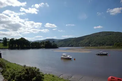 two boats on a river with mountains in the background at Tre-Allt Gorgeous Cottage in Dolgellau