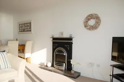 a living room with a fireplace and a tv at Ty Traeth Beach House in Tywyn