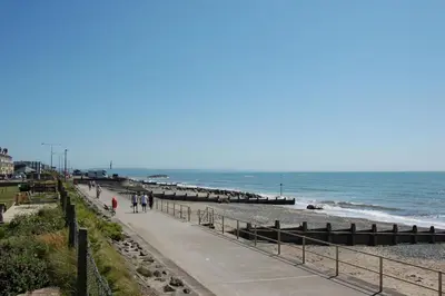 people walking on the beach near the ocean at Ty Traeth Beach House in Tywyn