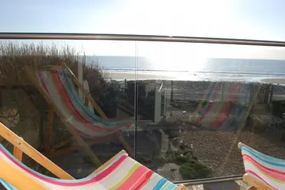 a view of the beach and two hammocks at Ty Traeth Beach House in Tywyn