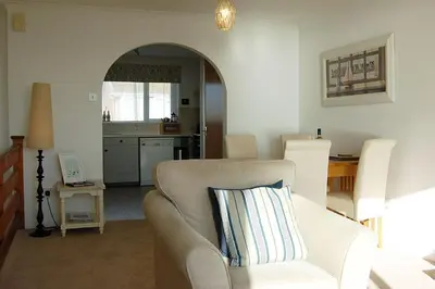 a living room with a couch and a kitchen at Ty Traeth Beach House in Tywyn