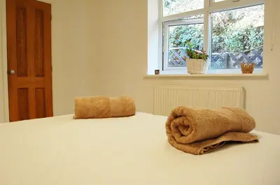 a bed with two towels sitting on top of it at Tawel Fryn Bungalow near Dolgellau in Dolgellau