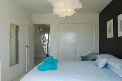 a bedroom with a white bed with blue pillows on it at Tywyn Beach House in Tywyn
